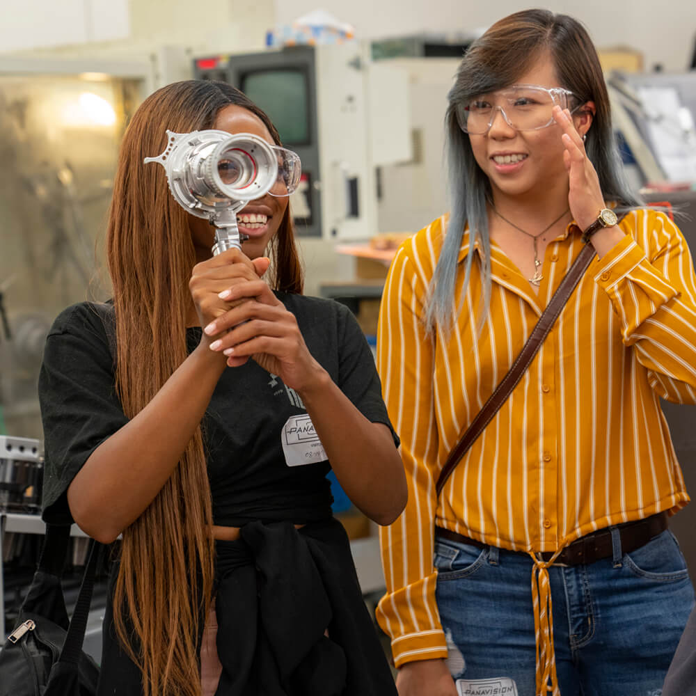 Young person smiling while looking through a half-manufactured directors viewfinder